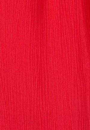 Tissu rouge vif avec des plis verticaux créant une surface froissée et texturée.