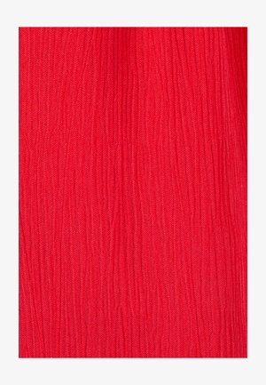 Tissu rouge vif avec des plis verticaux créant une surface froissée et texturée.