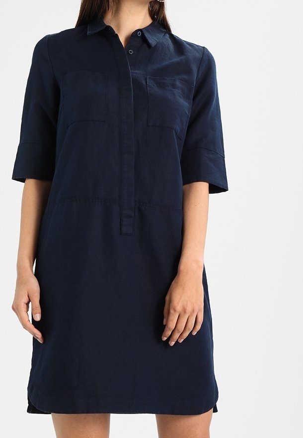 Robe chemise en lin bleu marine à manches courtes, boutonnée à l'avant, avec deux poches poitrine et un ourlet droit.