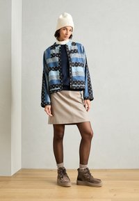 Farkkutakki sinimustilla kuvioilla, tumman neuleen päällä, yhdistettynä vaaleanbeigeen hameeseen ja ruskeisiin platform-botteihin.