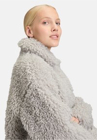 Lichtgrijze, donzige, oversized jas met een hoge kraag en textiel, die een zachte, pluche uitstraling heeft zonder zichtbare naden.