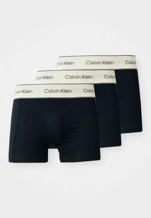 Three pairs of navy blue cotton boxer briefs with beige branded waistbands displaying "Calvin Klein." Smooth texture, fitted design.