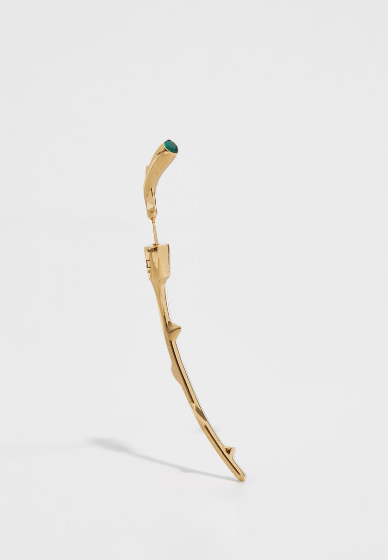 Boucle d'oreille en or en forme de branche courbée avec de petites épines et une pierre précieuse verte en accent à l'extrémité. Texture lisse, design moderne.