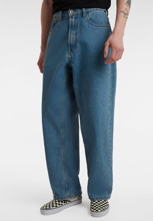 Lichtblauwe, wijde spijkerbroek met een hoge taille, knoopsluiting en denim structuur; gedragen met geruite instappers.
