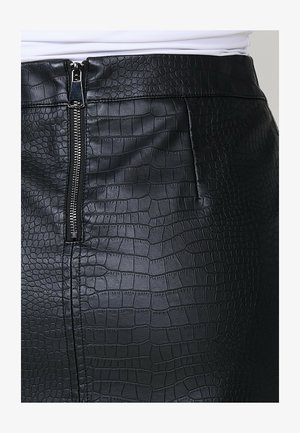 Fekete műbőr szoknya, amely texturált krokodilmintával rendelkezik, elől cipzárral záródik és karcsú sziluettel bír.