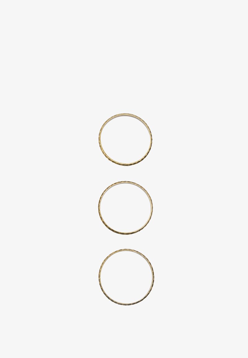 Trzy złocone metalowe pierścienie o różnych rozmiarach, z teksturowaną powierzchnią i subtelnymi różnicami w grubości.
