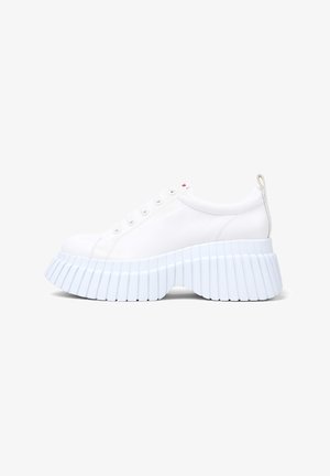 Witte sneaker met een ronde neus en een dikke, ribbelige lichtblauwe platformzool; beschikt over veterogen en een klein tabje op de hiel.