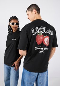 Black cotton t-shirt featuring a graphic of strawberries and Japanese text. Back design includes wording: "A fruity start to your day."