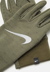 Gants en tricot verts avec un design texturé et le logo Nike en argent. Comprend un poignet côtelé et des détails contrastants en vert foncé.