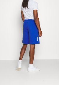 Blå träningsshorts i bomullsmix, med dragsko i midjan, sidofickor och en liten logotypdetalj på vänster sida.