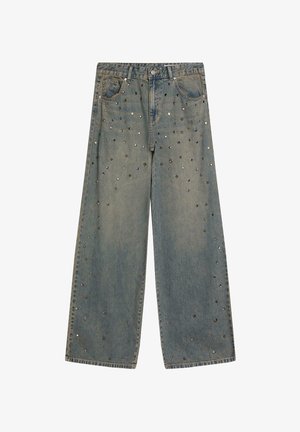 Wijd uitlopende, vervaagde blauwe spijkerbroek met verspreide metalen studs in verschillende vormen en maten aan de voorkant en op de zakken.