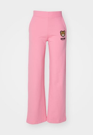 Pantaloni da tuta in cotone rosa con un design a gamba larga, caratterizzati da una grafica di un orso e il testo "MOSCHINO" sulla coscia sinistra. Tessuto morbido, cinturino elasticizzato.