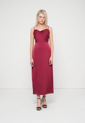 Bordó szatén ruha, ejtett nyakkivágással, testhez simuló felsőrésszel és légies szoknyával. Vékony pántokkal és a közép-vádliig érő hosszúsággal.