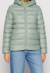 Lysegrøn dunjakke med lynlås foran, hætte og sidelommer. Har quiltede sektioner og en glat, blank tekstur.