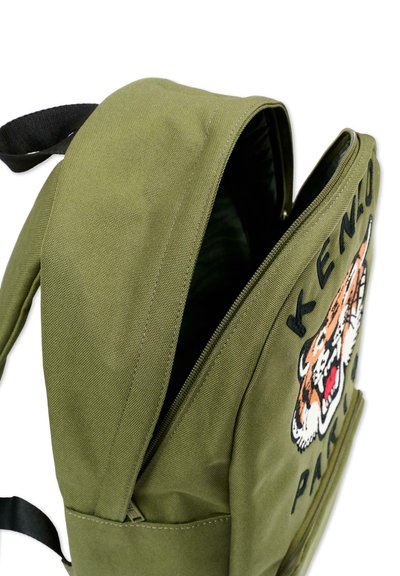 Sac à dos en tissu vert avec sangle noire, fermeture éclair partiellement ouverte, et broderie patch tigre avec le texte "KENZO PARIS" sur la poche avant.