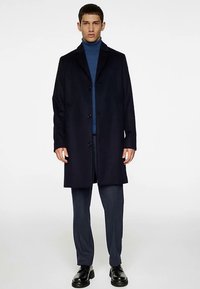 Marineblauwe overjas van een wolmix met een getailleerde pasvorm, een enkelrijig ontwerp, drie knopen en een contrasterende coltrui eronder.