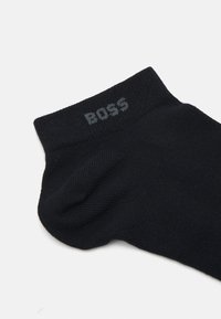 Schwarze Socke mit gerippter Textur, mit dem eingewebten Logo "BOSS" am oberen Rand. Knöchellanges Design für Komfort und Passform.