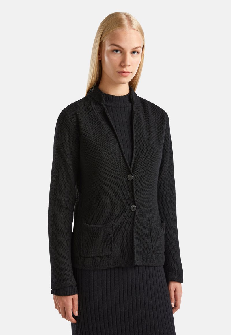 Černý pletený kardigan s texturovaným povrchem, bez límce, se dvěma předními kapsami a jednobodovým zapínáním.