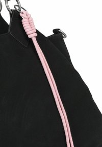 Sac à main en suede noir avec une finition texturée, orné d'un détail en corde rose et de garnitures en métal argenté. Les accents incluent des anneaux ronds.