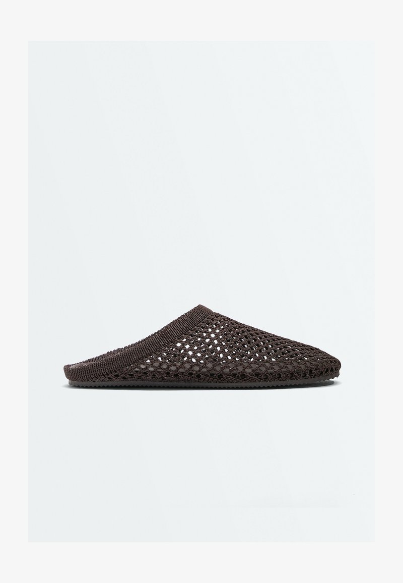 Mule marron foncé en tissage ouvert, à enfiler, avec une semelle plate et un bout fermé arrondi, présentée sur un fond clair uni.