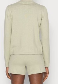 Jasnozielony zestaw do wypoczynku z dzianiny, składający się z długiego rękawa topu z żebrowanym dekoltem oraz dopasowanych szortów z prostym wykończeniem.