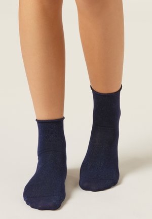 Calcetines tobilleros azul marino con una textura brillante, que presentan un puño acanalado y un acabado suave. Adecuados para uso casual.
