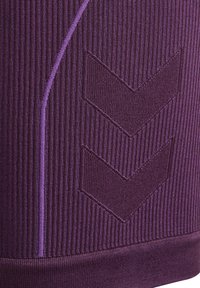 Paarse sportstof heeft verticale ribbelstructuur, een gladde textuur en contrasterende zigzagaccentpatronen in donkerder paars.