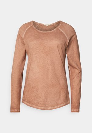 T-shirt à manches longues, col rond en tissu doux de teinte pêche avec une finition légèrement texturée et des coutures claires contrastantes. Ourlet incurvé subtil.