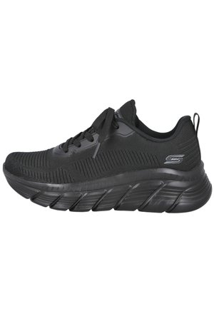 Zapatilla deportiva Skechers negra con parte superior de tejido, suela acolchada gruesa, cierre de cordones y logo de la marca en el lateral del talón.