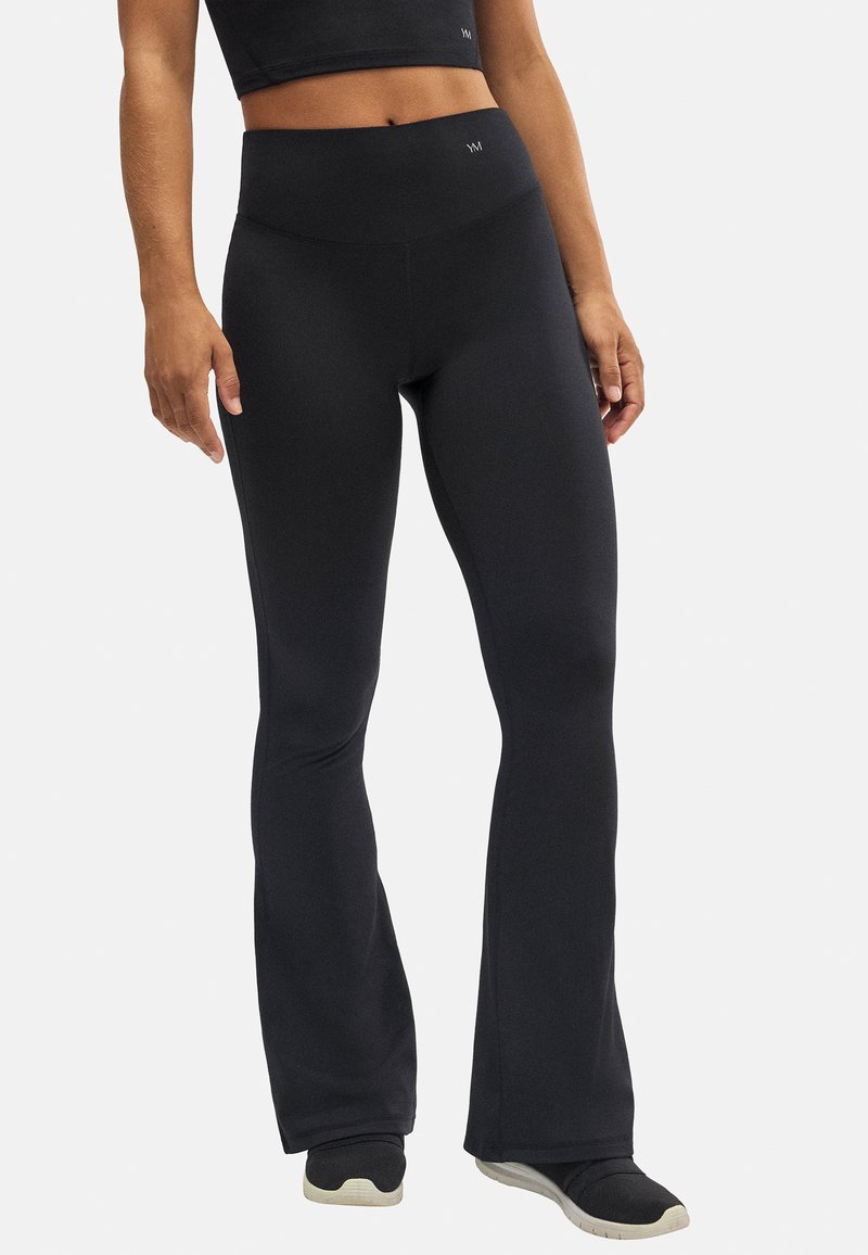 Leggings negros acampanados hechos de una tela elástica con una cintura alta. Presentan una textura suave y un branding mínimo en la cintura.