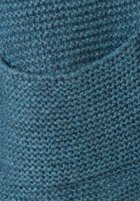Strukturierter blauer Stoff mit einem gestrickten Muster. Das Material wirkt weich und zeigt eine subtile Mischung aus dunkleren und helleren Blautönen.