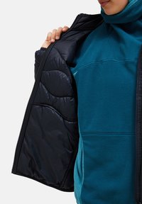 Gevoerde jas met een teal fleece buitenkant en een zwarte gestikte voering, voorkant met rits en hoge kraag voor extra warmte en comfort.