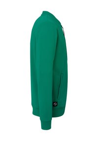 Grøn sweatshirt med en glat tekstur, fuld lynlås og sidelommer. Har en opretstående krave og et logo nederst til venstre.