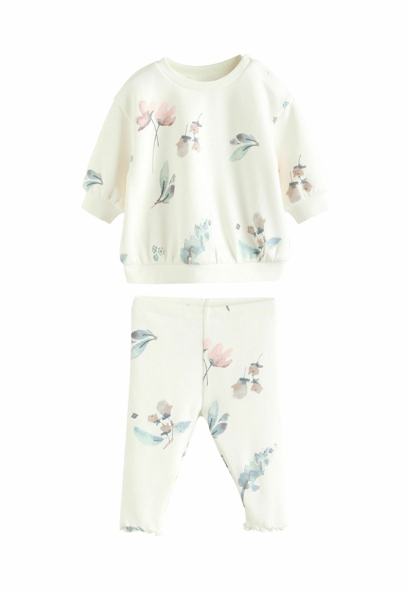 Sæt i bomuld til afslapning i creme farve med pink og blå blomsterprint. Det indeholder en kortærmet pullover og leggings med elastisk talje samt flæser ved kanten.