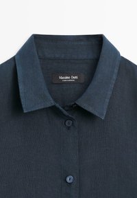 Ciemnoniebieska lniana koszula z szpiczastym kołnierzykiem i guzikami, z naszywką marki Massimo Dutti wszytą wewnątrz dekoltu.