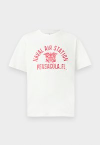 Balta trumpa rankovėmis marškinėliai su raudonu tekstu "JŪRŲ AVIACIJOS STOTIS PENSACOLA, FL." ir erelio emblema centre priekyje.