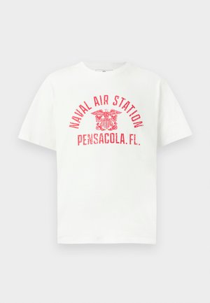 Valkoinen lyhythihainen T-paita, jossa on punainen teksti "NAVAL AIR STATION PENSACOLA, FL." ja kotka-embleemi keskellä edessä.