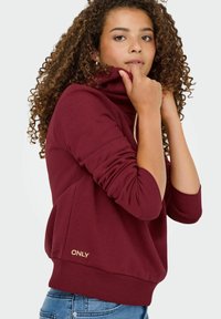 Mørkerød hoodie med høj krave, ribbede cuffs og kant. Har et guld "ONLY" logo foran. Glat tekstur, afslappet design.