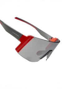 Szürke keretes, piros díszítéssel ellátott napszemüveg, nagy, tónusú lencsével és modern, letisztult dizájnnal. A "Hawkers" márkanév jól látható a kereten.