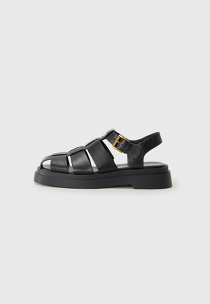 Sandales en cuir noir avec des brides entrecroisées, design ouvert à l'avant, semelle en caoutchouc épaisse et accent de boucle en métal doré sur le côté.