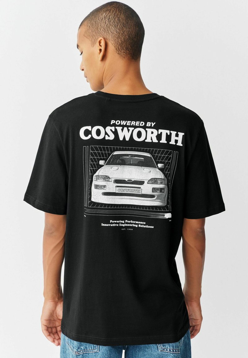 Camiseta de algodón negra con un gran estampado gráfico de un coche y el texto "Impulsado por Cosworth" en la parte trasera. Manga corta; corte relajado.