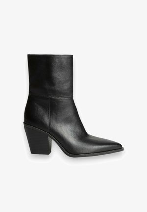 Botín negro de cuero hasta el tobillo con puntera afilada, parte superior texturizada, detalles en las costuras laterales y tacón cuadrado apilado.