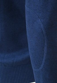 Ciemnoniebieski sweter z ryflowanym dołem i detalicznym przeszyciem; miękka tekstura z bezszwowym wykończeniem. Akcentująca kieszeń na rękawie.