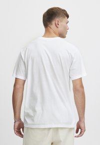 Hvid bomulds T-shirt med korte ærmer og rund halsudskæring, der har en ensfarvet overflade og en afslappet pasform. Ingen synlige mønstre eller grafikker.