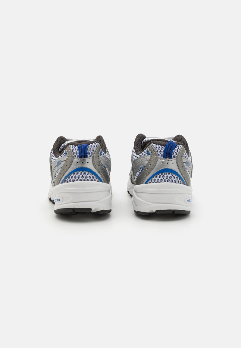 Zapatillas deportivas grises y azules con parte superior de malla, lengüeta acolchada y suelas de goma. Presenta un acento texturizado y detalles de color en contraste.