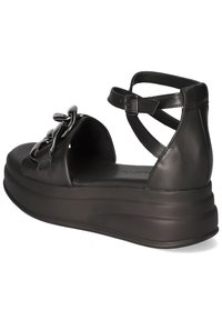 Svarta läderplattformsandaler har ett brett rem som pryds av en kedjedetalj, ankelremmar och en slät, strukturerad sula.