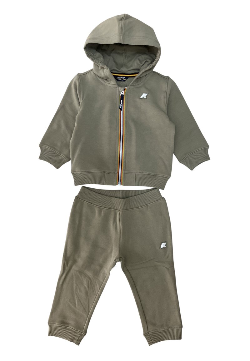 Tuta verde oliva con felpa con zip e pantaloni coordinati. Presenta polsini a coste, un logo sulla giacca e un rivestimento interno a contrasto.