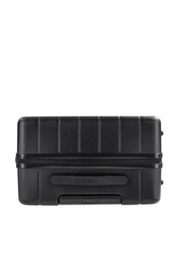 Zwarte hard-shell koffer met verticale groeven, ritssluiting en logo. Compact ontwerp met afgeronde hoeken en een gevormde handgreep. Duurzame textuur.