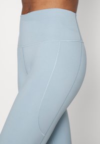 Jasnoniebieskie legginsy z wysokim stanem, wykonane z elastycznego materiału, z płaskimi szwami i gładką teksturą, zaprojektowane z myślą o komforcie i elastyczności.
