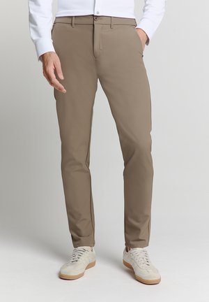 Beige chino's van lichtgewicht stof met een slim fit, voorzien van zijzakken en een knoopsluiting, gecombineerd met witte sneakers.